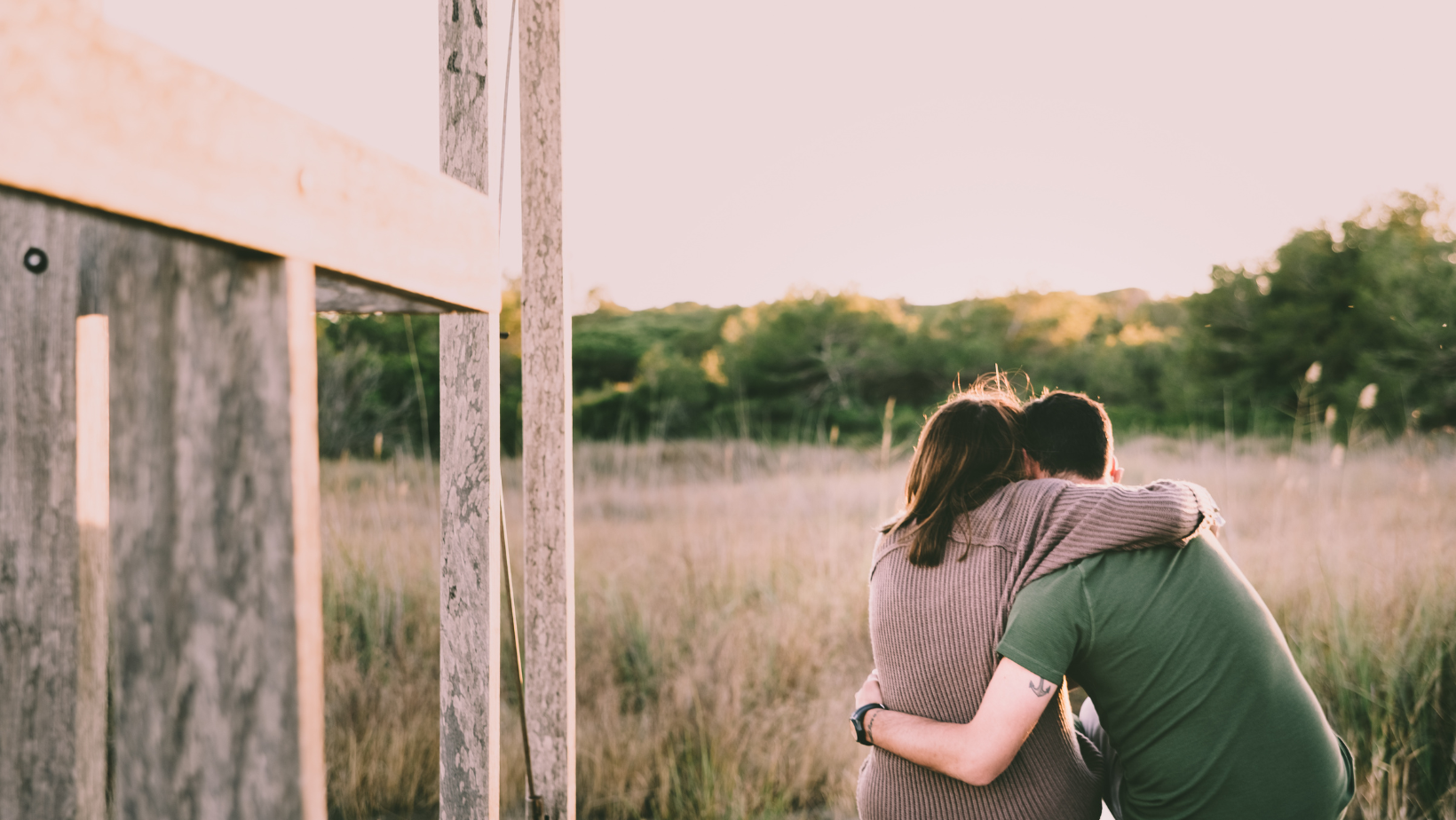 Man and women embracing infront of a field of grass